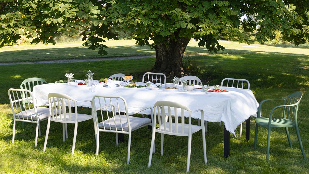 Bohem Brevik stoler plassert rundt et avlang bord med hvit duk på en gressplen.