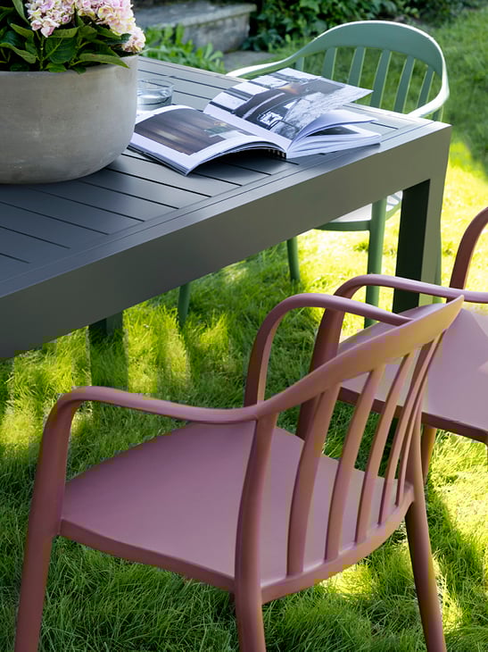 Bohem Vika stol i Dusty Burgundy rundt Naterial Lyra II uttrekksbord i en hage. 