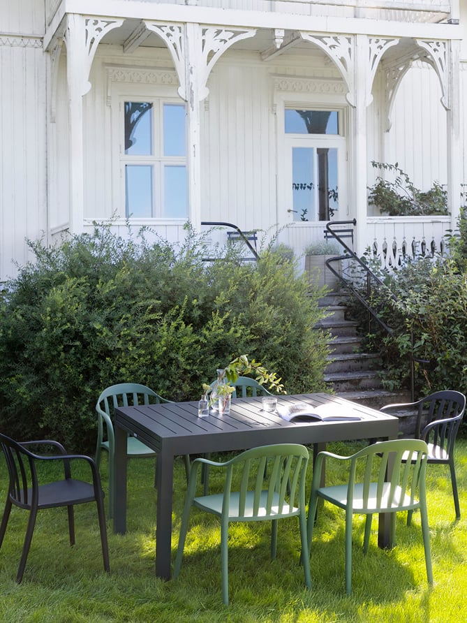 Bohem Vika stoler rundt Naterial Lyra II uttrekksbord i en hage. 