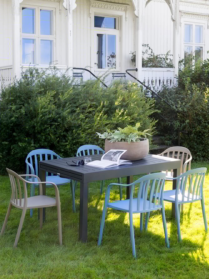 Bohem Vika stol i Blue Shadow rundt Naterial Lyra II uttrekksbord i en hage.