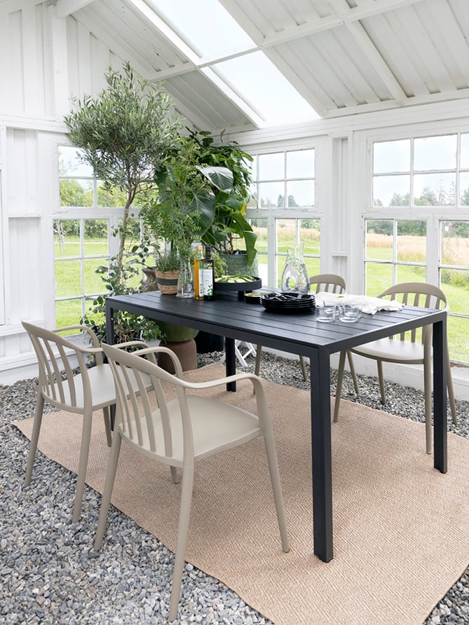 Bohem Vika stol i Timber Wolf rundt et sort spisebord i en hagestue.