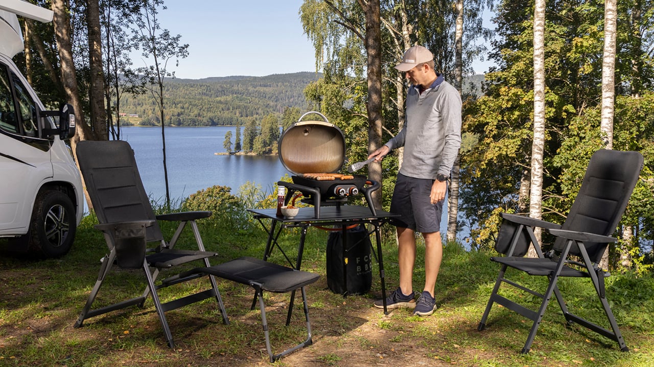 En mann som griller pølser på en campingsplass.