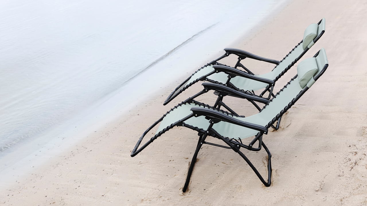 Bohem Baden stoler i moss green på en strand.