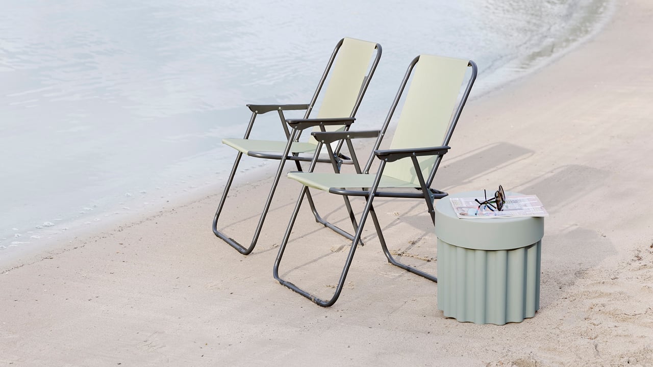 Bohem campingstol med et bord ved siden av på en strand.