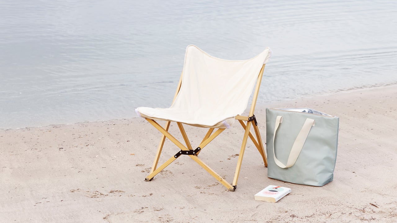 Ullerøy glampingstol på en strand med en bag ved siden av. 