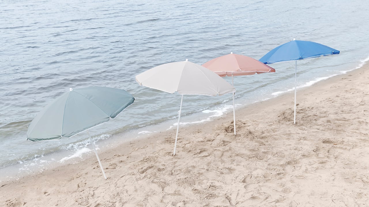 Bohem strandparasoller i fire forskjellige farger på en strand.