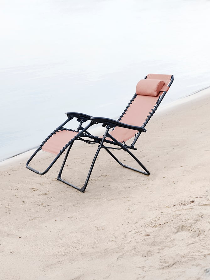 Bohem Baden stol i Dusty Coral på en strand. 