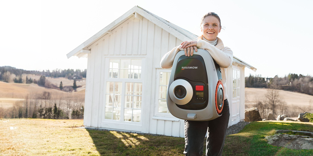 Tiril poserer foran hus med robotklipper til navimow