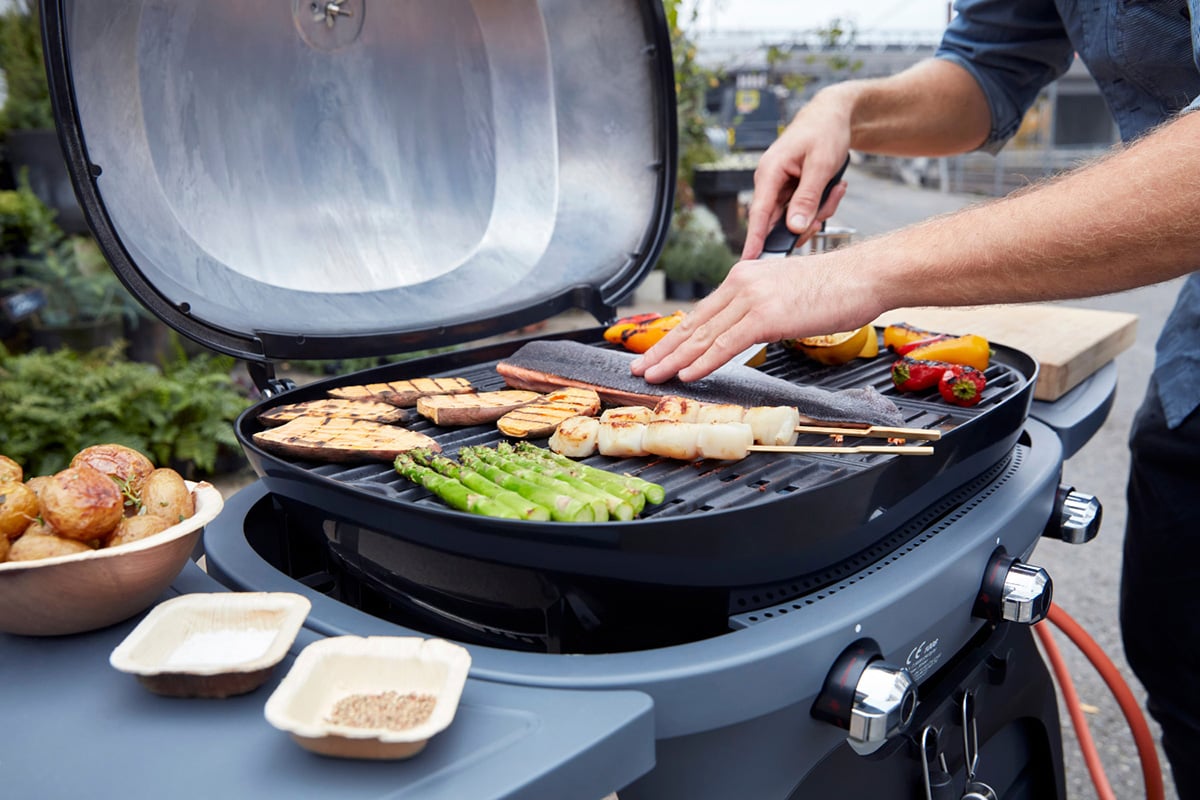 En mann som griller fisk og grønnsaker på en gassgrill