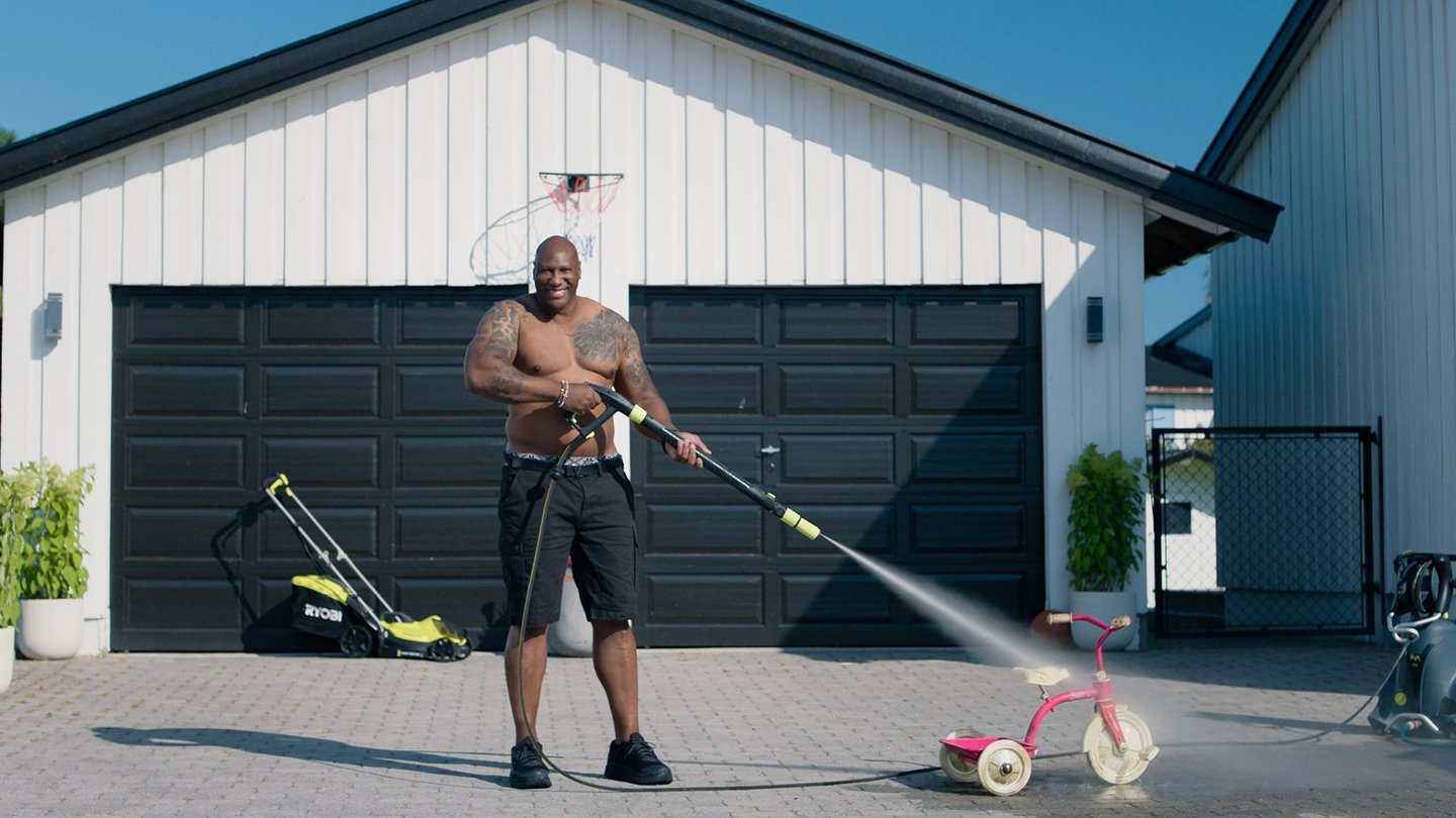 Mann som vasker lekesykkel på parkering