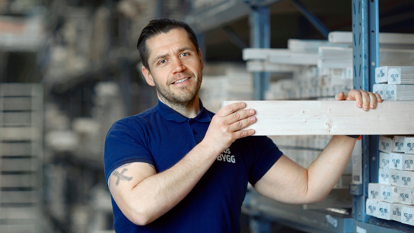 Mann med Obs BYGG uniform tar ut en planke i varehus