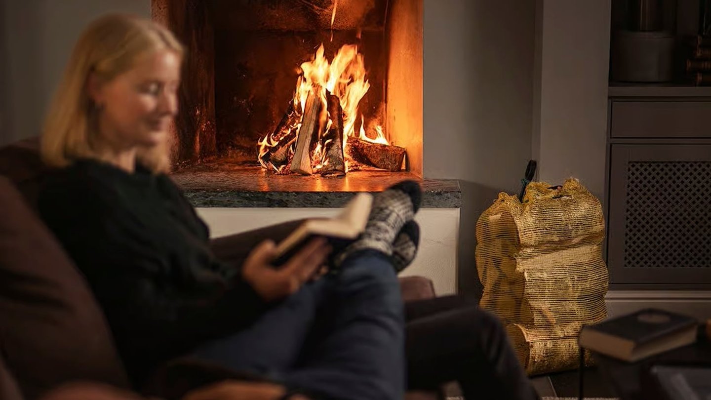 Dame sitter foran peis og koser seg