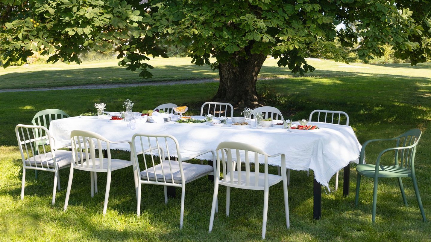 Vika og Bohem Brevik stoler rundt et bord med hvit duk på en gressplen