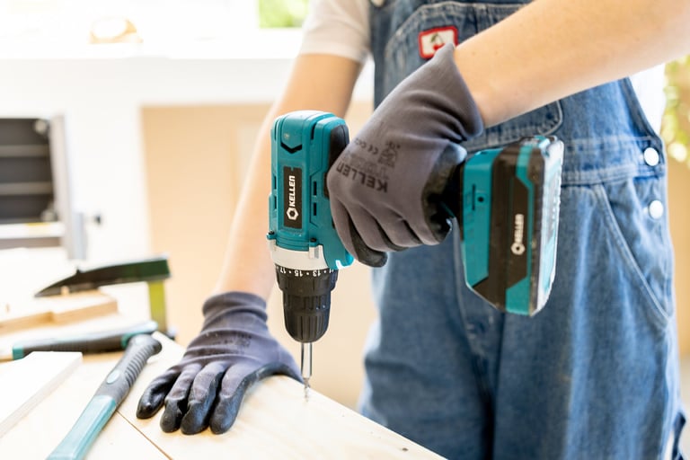 En person som skrur inn en skrue med en batteridrevet drill fra Kellen