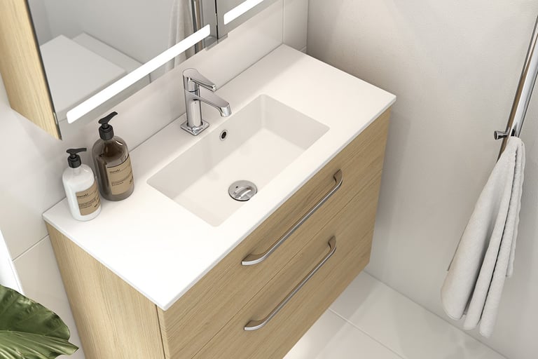 Servantskap i lyst treverk med hvit servantplate på lite bad.