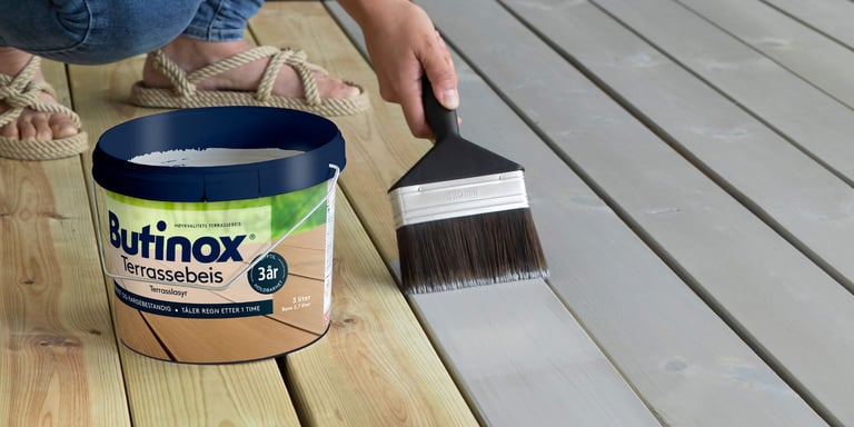 Et Butinox terrassebeis spann som står på en terrasse, med grønn og frodig bakgrunn.