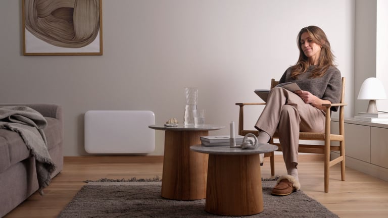 Kvinne slapper av i stue med hvit panelovn på veggen.