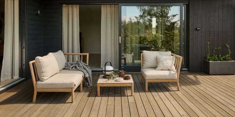 Et uteplass med grønne vegger, sofa og grønne planter som står terrassen.