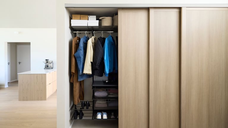 Skyvedørsgarderobe i lys eik med åpen seksjon og organisert oppbevaring av yttertøy og sko.