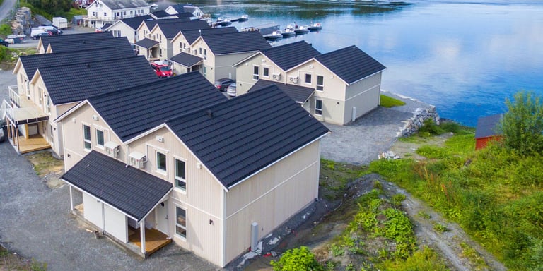 Bilde av to rekker med hus med tak i modellen Powertekk fra Isola. Husene er hvite og takene er svarte. Husene står ved sjøen.