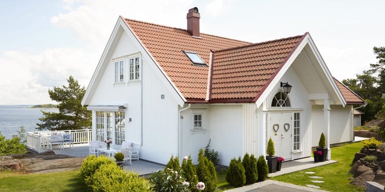 Hvit hus langs vannet i grønne omgivelser