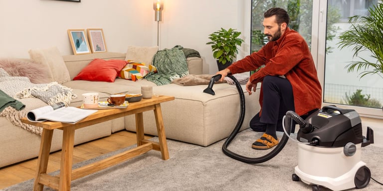 Mann som bruker tekstilrenser fra Kärcher for å vaske sofaen