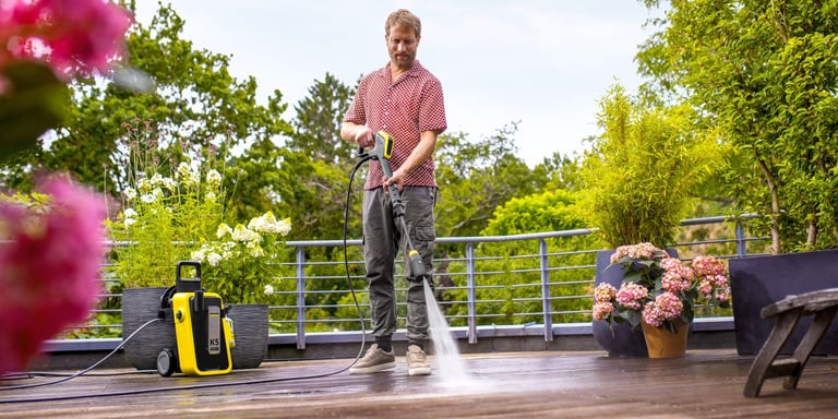 Mann står med høytrykkspyler og vasker terrassen med maskin fra Kärcher
