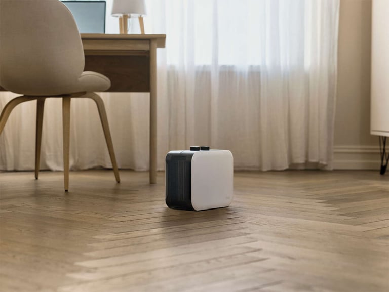 Kvinne som ser ut av et vindu med kopp i hånden på sofaen.